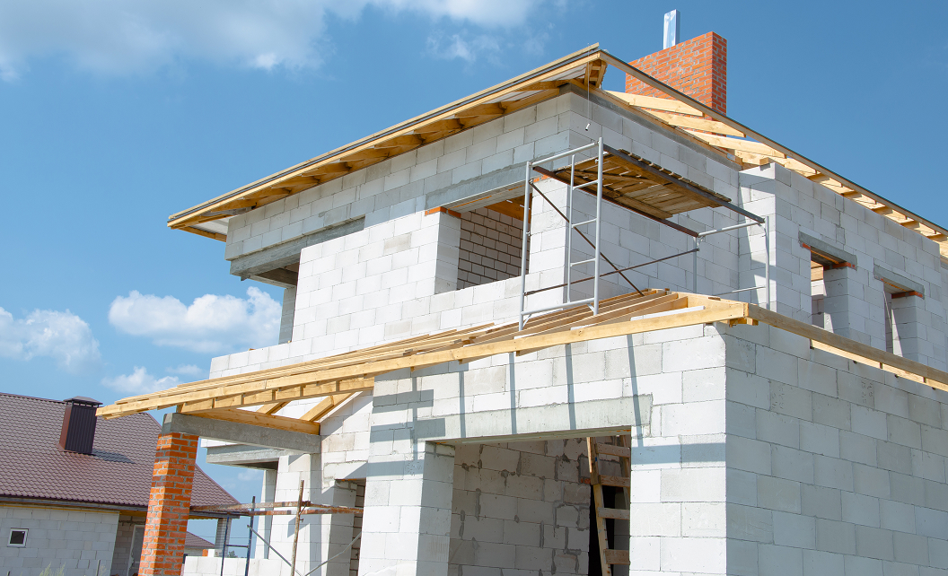 Vue d’une maison individuelle en construction, façade non terminée, illustrant le choix des matériaux et du style extérieur