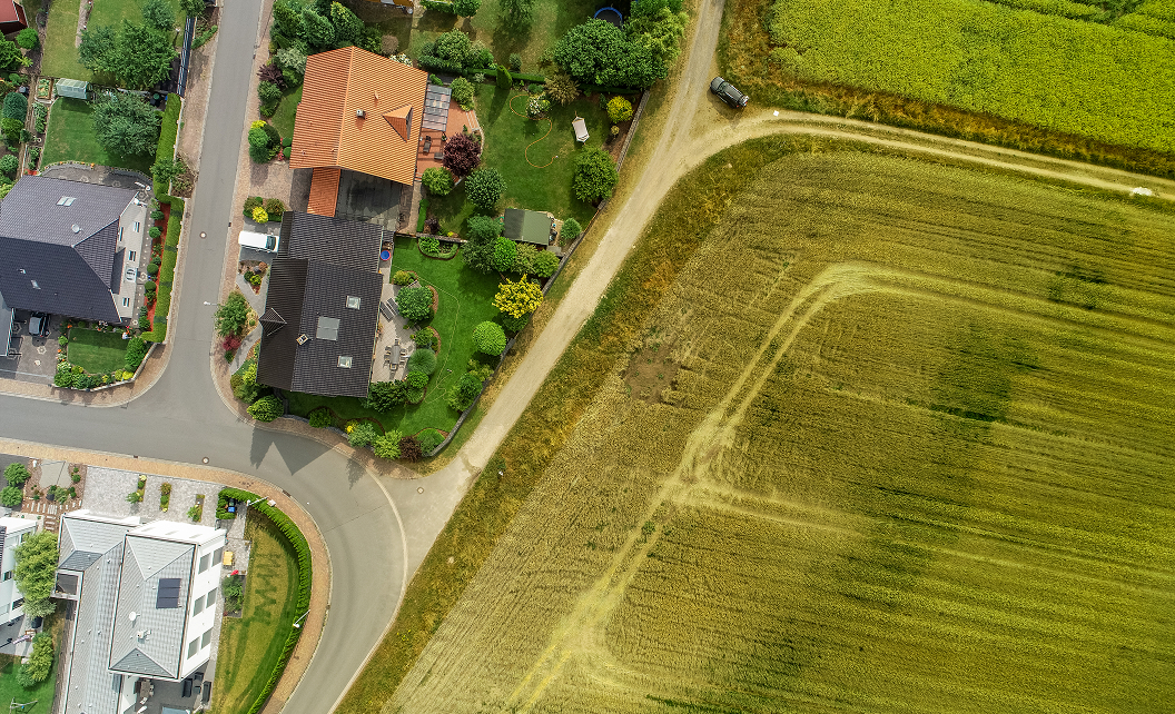 Vue aérienne d’un lotissement avec maisons construites à côté de terrains agricoles non viabilisés