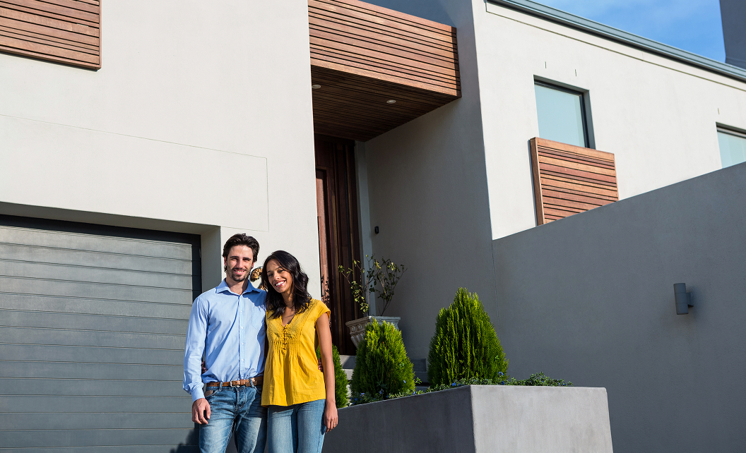Couple souriant devant une maison neuve moderne en Île-de-France, symbolisant un projet immobilier réussi avec Domexpo